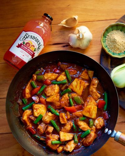 Blood Orange Sweet & Sour Pork in a pan with added garlic and Bundaberg Brewed Drink Blood Orange.