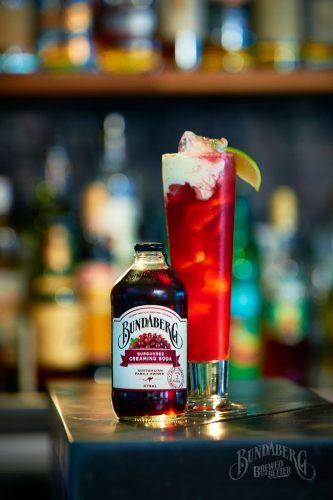 Cranberry Trifle Mocktail on bar with Bundaberg Burgundee Creaming Soda garnished with lime wedge